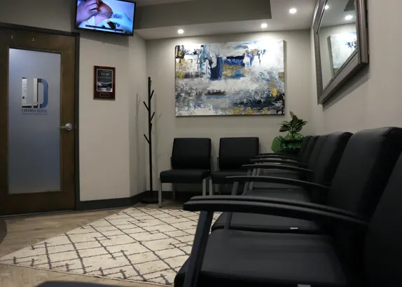 Waiting room with black leather chairs, a rug, artwork and a wall-mounted screen