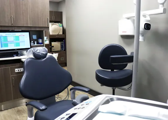 Treatment room with the chair, a monitor showing digital records and a wall-mounted X-ray head