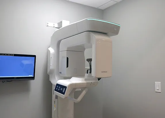 VATECH panoramic and 3D imaging unit standing beside a wall-mounted monitor